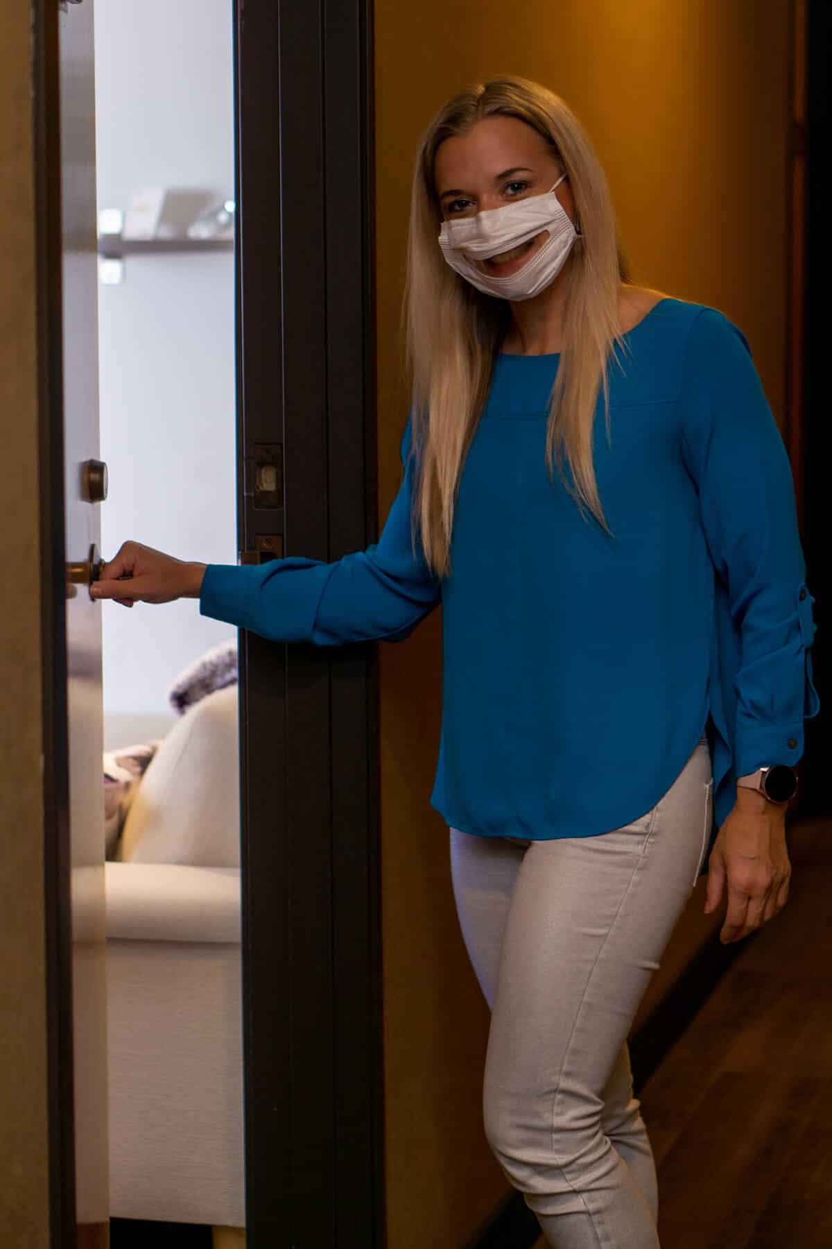 Woman Holds door open with mask on